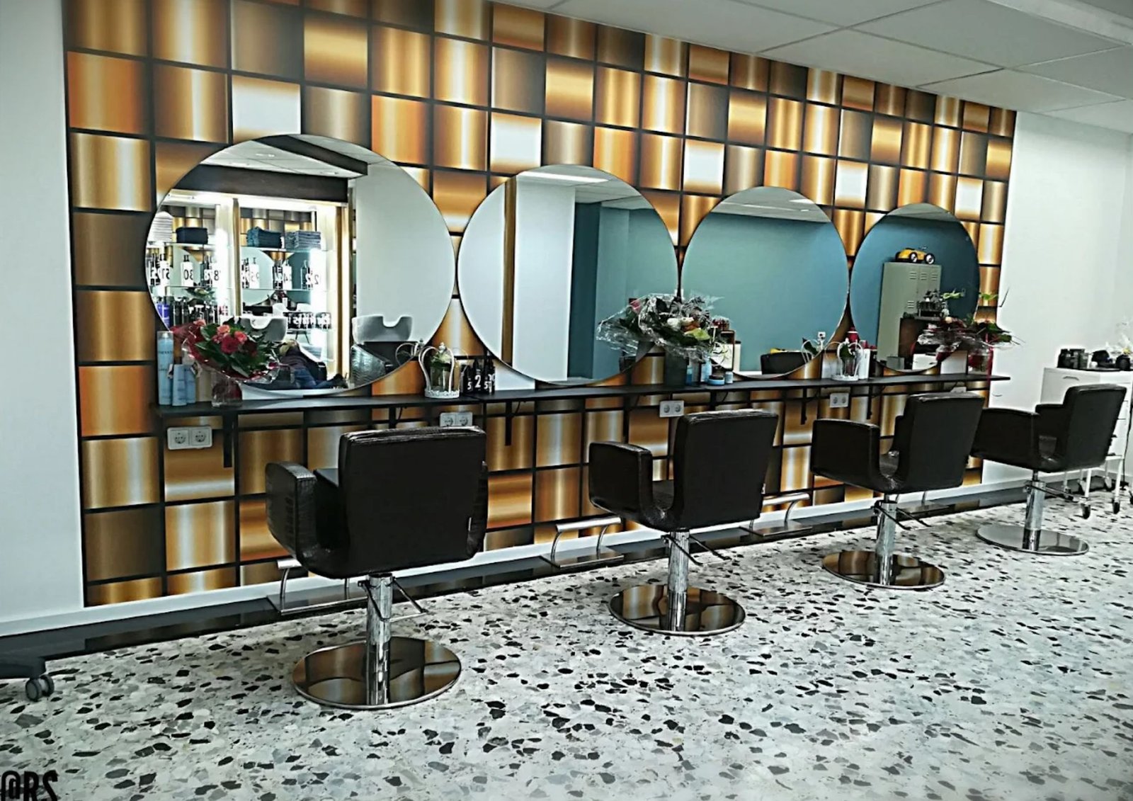 Interior view of Styling bij Tamara salon in Kerkrade with retro gold wall panels, round mirrors, and styling chairs
